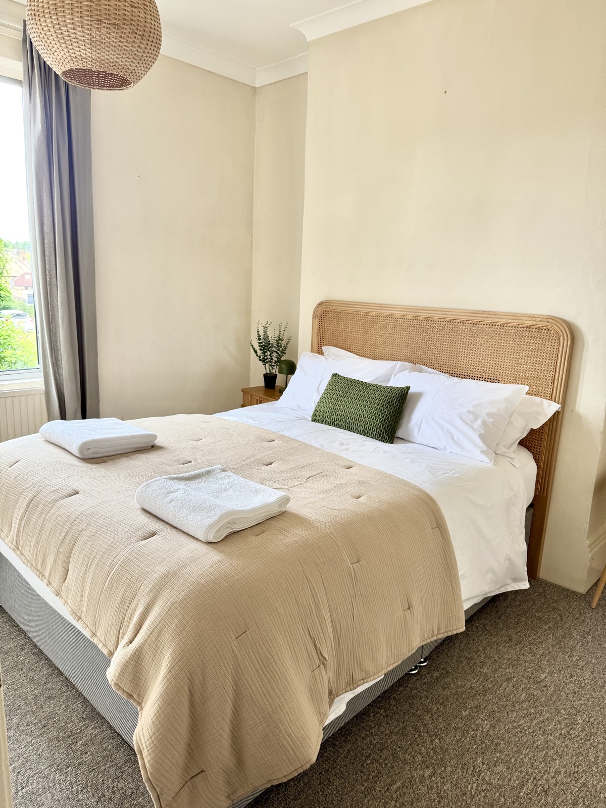Double bedroom with a cane headboard and crisp white linen