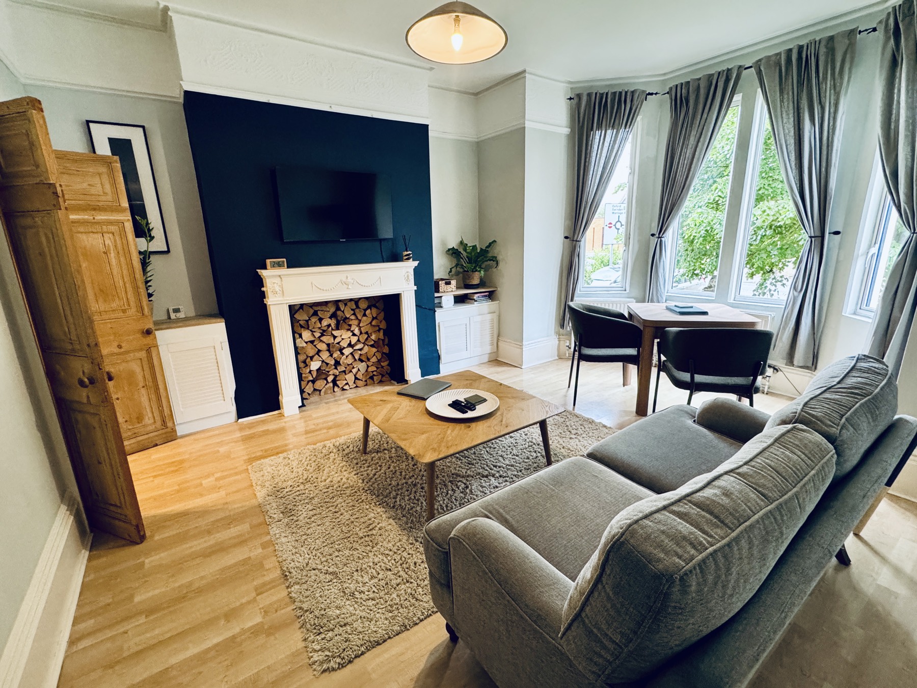 Living room with a grey sofa, coffee table and dining area by the bay window